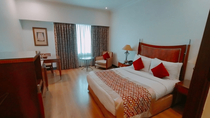 Spacious bedroom with king bed and seating area at Hotel Hindusthan International, Kolkata.