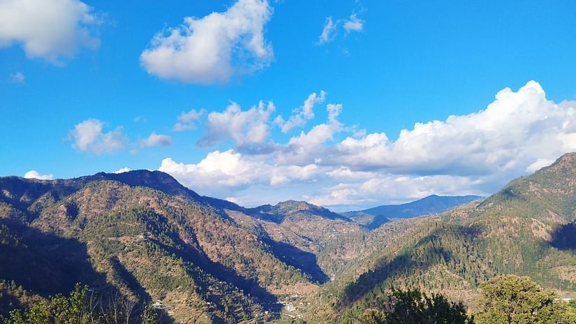 View of lush mountains with a blue sky with could scattered around