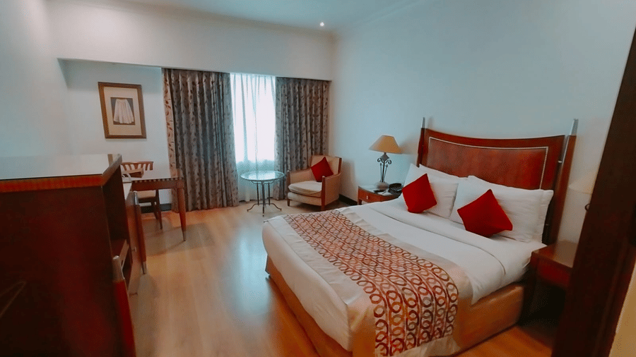 Spacious bedroom with king bed and seating area at Hotel Hindusthan International, Kolkata.