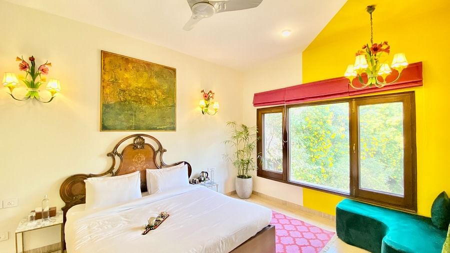 An image showing the King sized bed with soft mattress and pillows and a corner sofa, a nailed art on the wall, overseeing the beautiful garden.