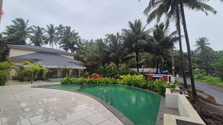 Swimming pool area surrounded by trees at Lamrin Morjim Goa
