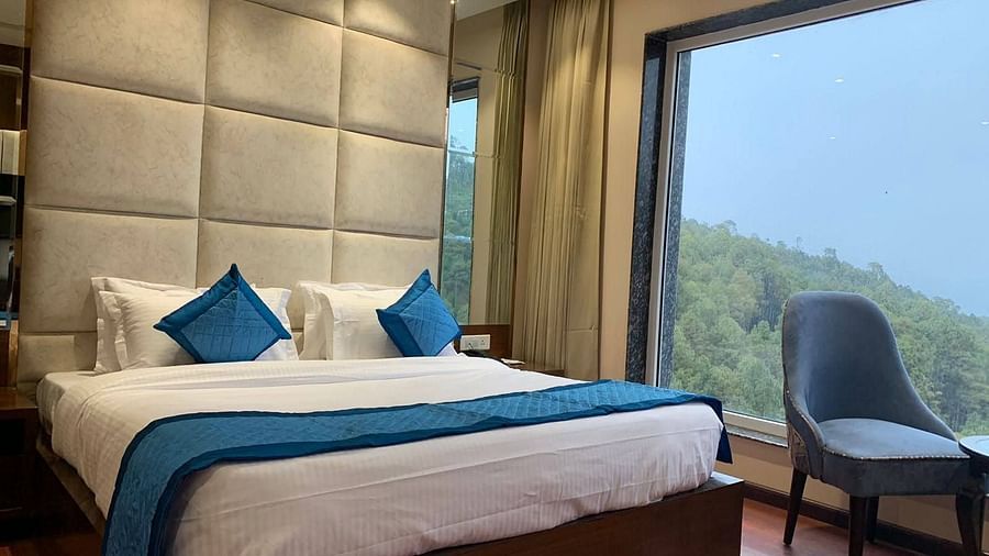 Side view of Deluxe room with plush bed and bedside tables, seating area with coffee table - Mastiff Hotel, Dalhousie
