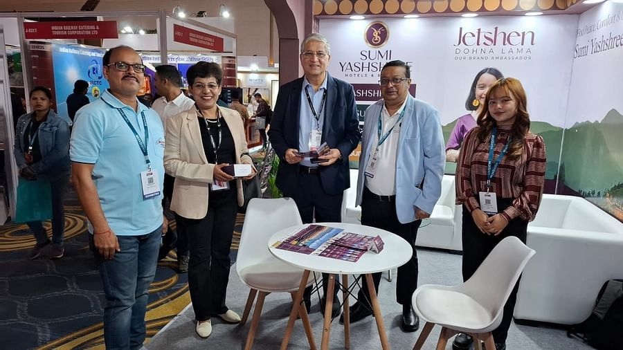 Group photo at the Sumi Yashshree Hotels & Resorts booth, featuring team members and visitors engaged in a professional event setting.