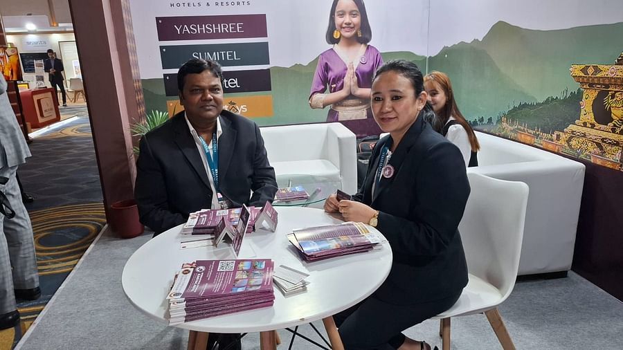 Two representatives seated at an elegantly designed exhibition booth for Sumi Yashshree Hotels & Resorts, engaging with promotional material. 