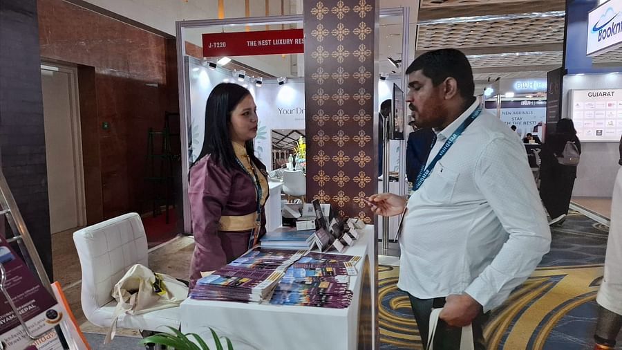 Two individuals engaged in a discussion at an exhibition booth, showcasing promotional materials for Sumi Yashshree Hotels.
