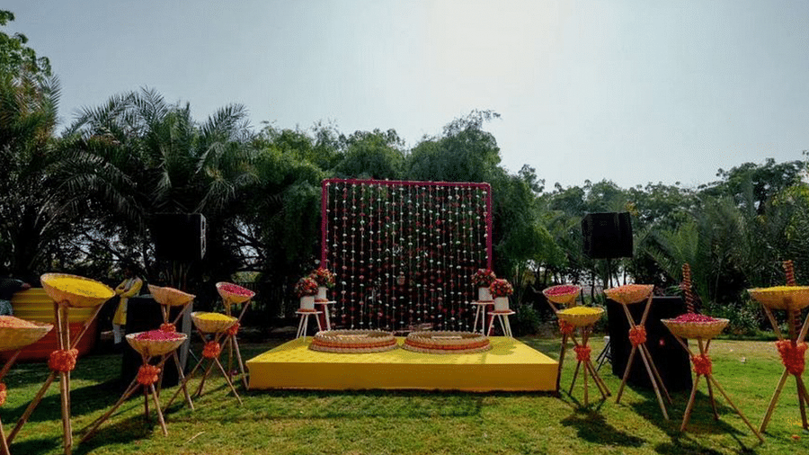 Outdoor wedding stage fully decorated at The Ummed Jodhpur, with a floral backdrop, colorful seating arrangements, and a lush green lawn.