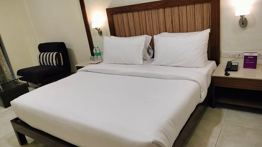 An image of Deluxe King Room featuring a bed, bedside table on either side, and a sofa - VITS Lonavla