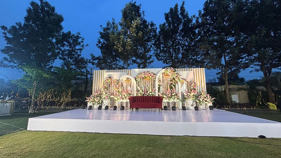 Outdoor wedding stage with a floral backdrop, raised platform, and a flower aisle.