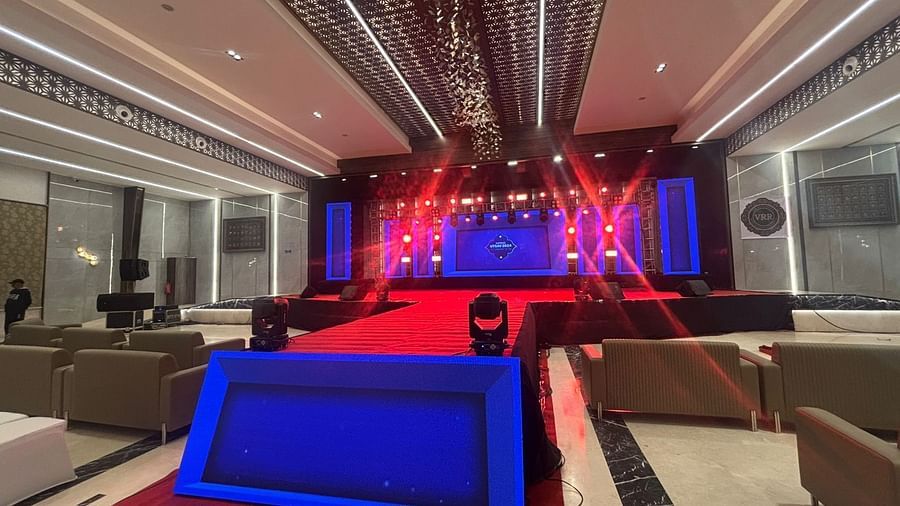 Conventional hall with chairs, a stage, and red carpet.
