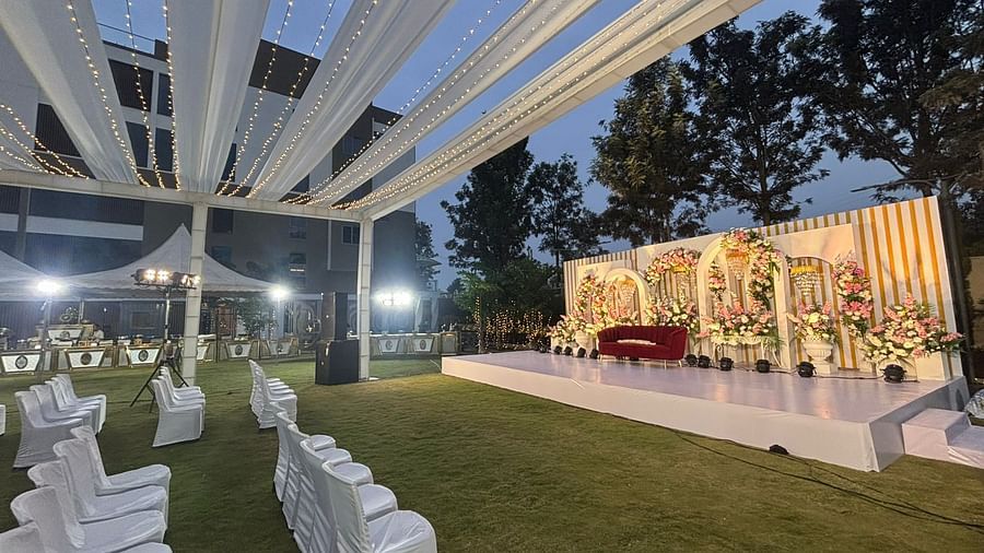 Outdoor wedding ceremony with a flower aisle and white chairs facing the stage.