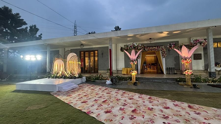 Outdoor wedding stage with a floral backdrop, raised platform, and a flower aisle.