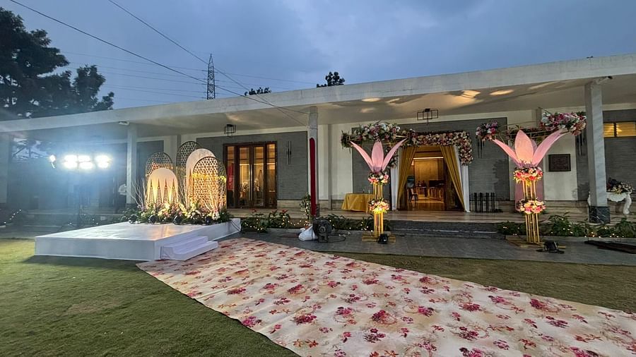 Outdoor wedding ceremony with a pink flower aisle leading to a gazebo-like structure.