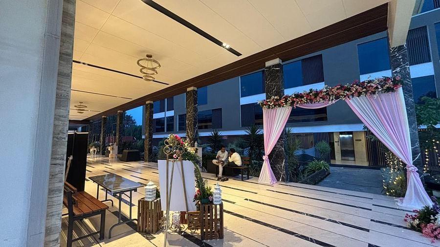 Indoor reception hall with round tables adorned with floral centerpieces and a stage in the background.