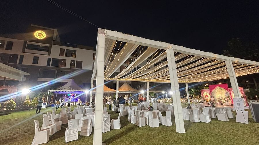 Night-time view of an outdoor event setup with white canopies, chairs arranged in rows, and decorative lights on the lawn.