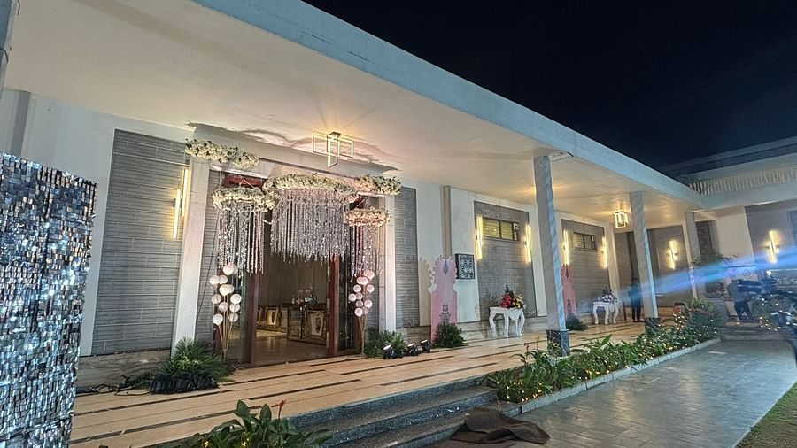 Exterior view of an elegantly lit entrance with glass doors and decorative lights at night.