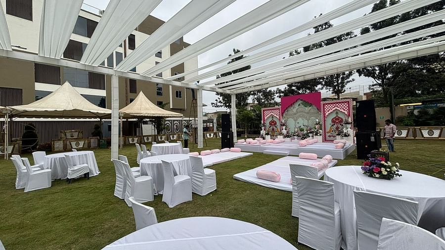  Daytime view of an outdoor dining area featuring a white canopy, round tables, and chairs on a lawn.