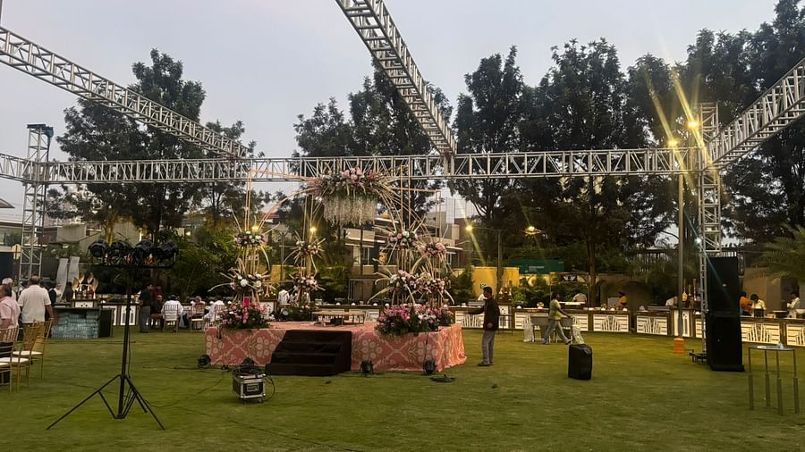 A large open lawn with a stage, lighting rig, and sound equipment, ready for an outdoor event.