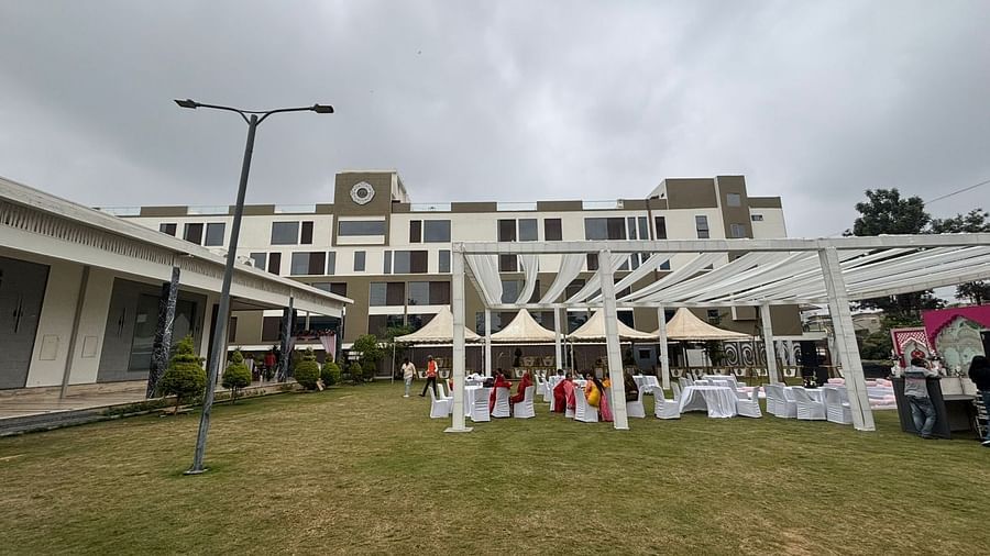  Daytime view of an outdoor dining area featuring a white canopy, round tables, and chairs on a lawn.