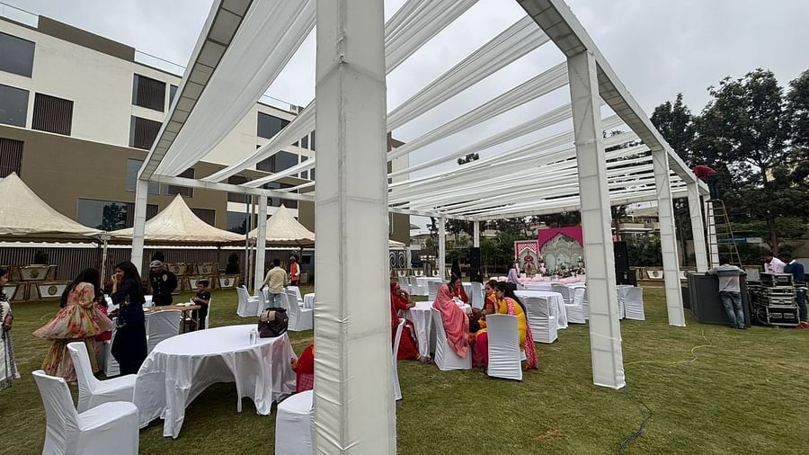 Outdoor event area with white canopies, decorated tables, and chairs set up on a green lawn.
