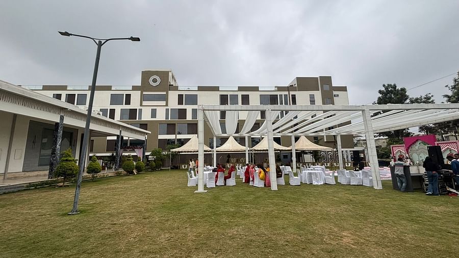 Outdoor event setup featuring a lawn with white canopies, tables, and chairs, with a modern building in the background.
