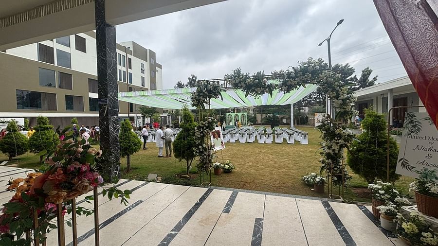A beautifully landscaped outdoor area featuring decorative plants, paved pathways, and a view of the event venue.