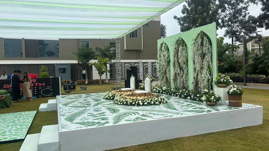 An outdoor event lawn with seating arrangements under a canopy, surrounded  lawn.