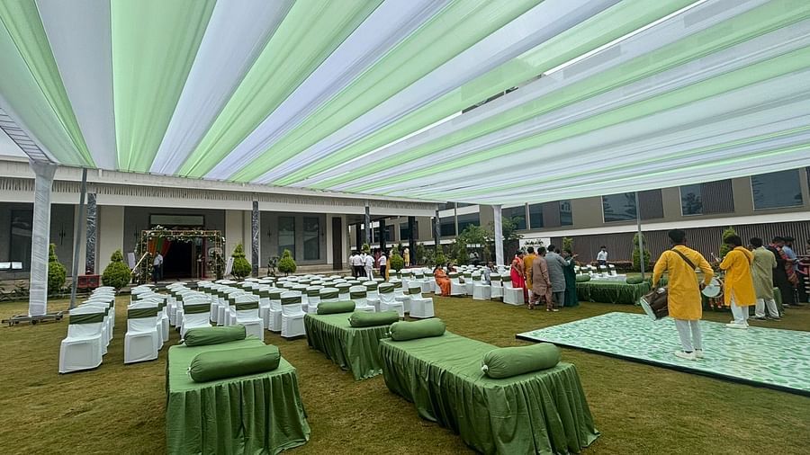A spacious outdoor venue with a canopy, lawn chairs, garden in the background.