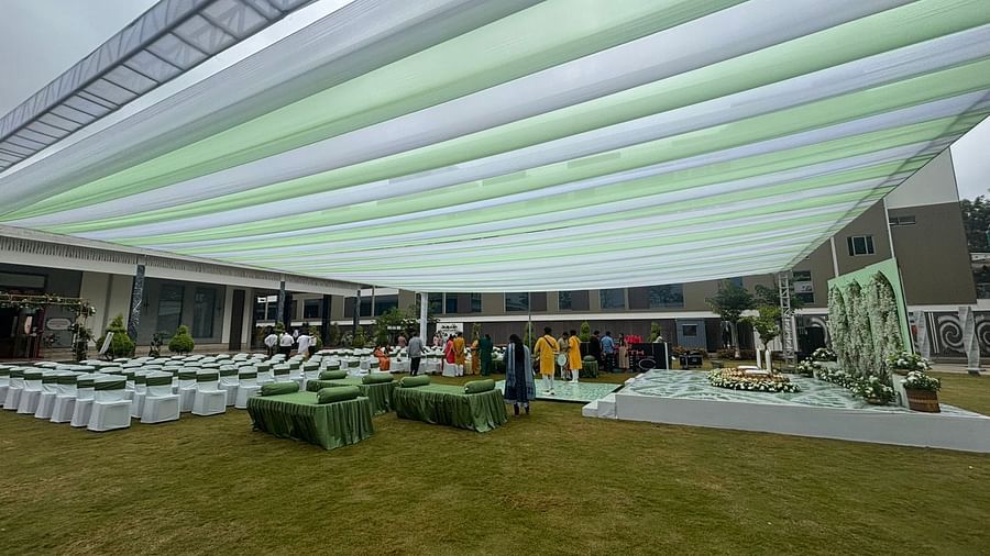 A spacious outdoor venue with a canopy, lawn chairs, garden in the background.