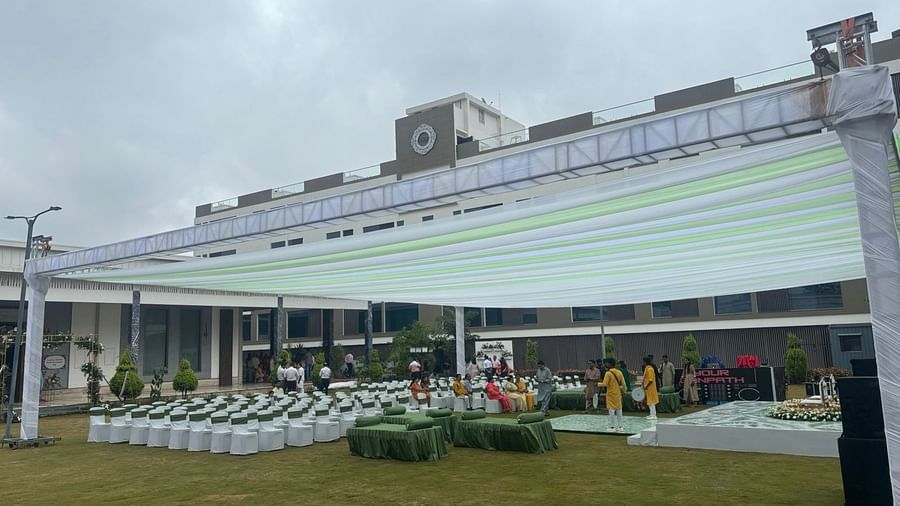 A spacious outdoor venue with a canopy, lawn chairs, garden in the background.