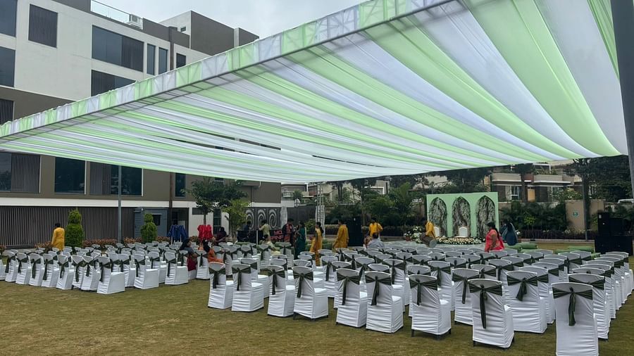 A spacious outdoor venue with a canopy, lawn chairs, garden in the background.