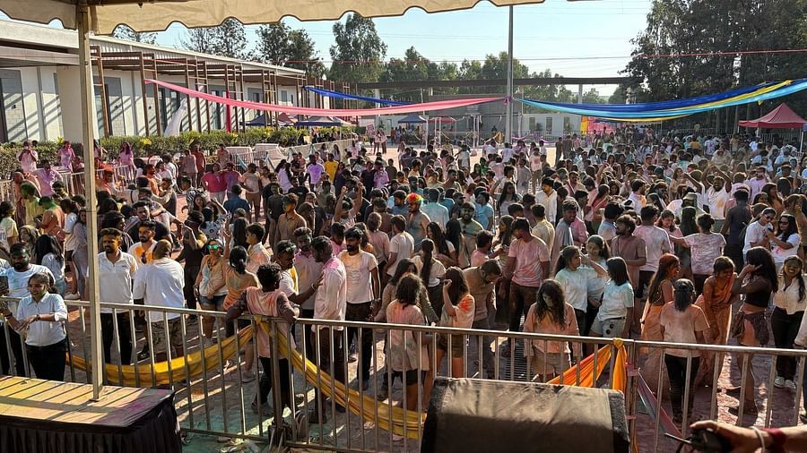 Picture of the crowd, people standing and sitting, colorful decorations overhead, stage area visible.