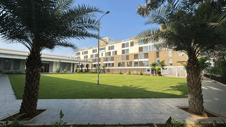A facade of VRR Astoria Hotel under a clear sky featuring lawn and pavements