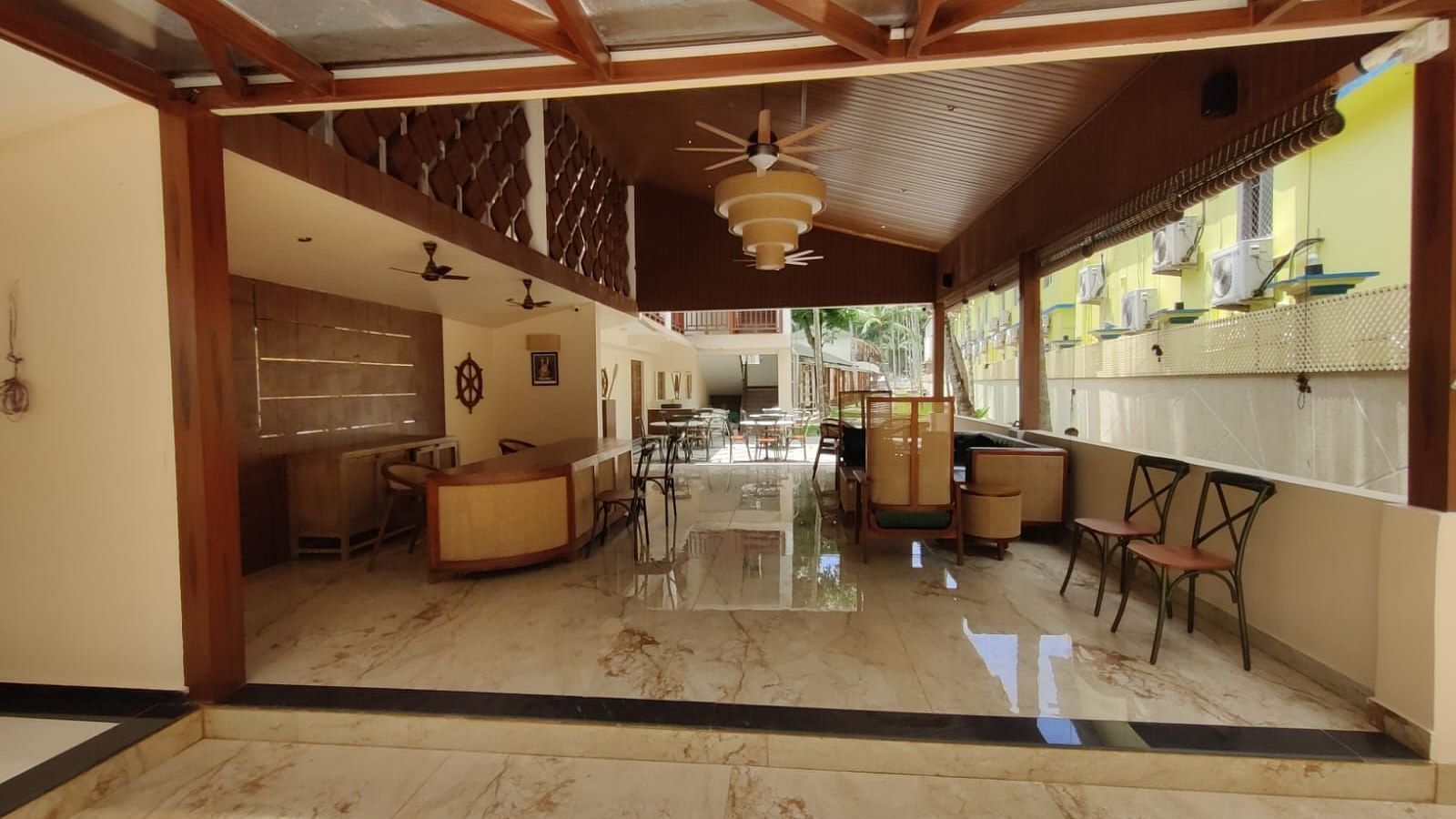 Shot of the reception at the resort featuring some chairs and a front desk Image of the swimming pool in the resort surrounded by trees with clear sky in background | Arina Island Resort