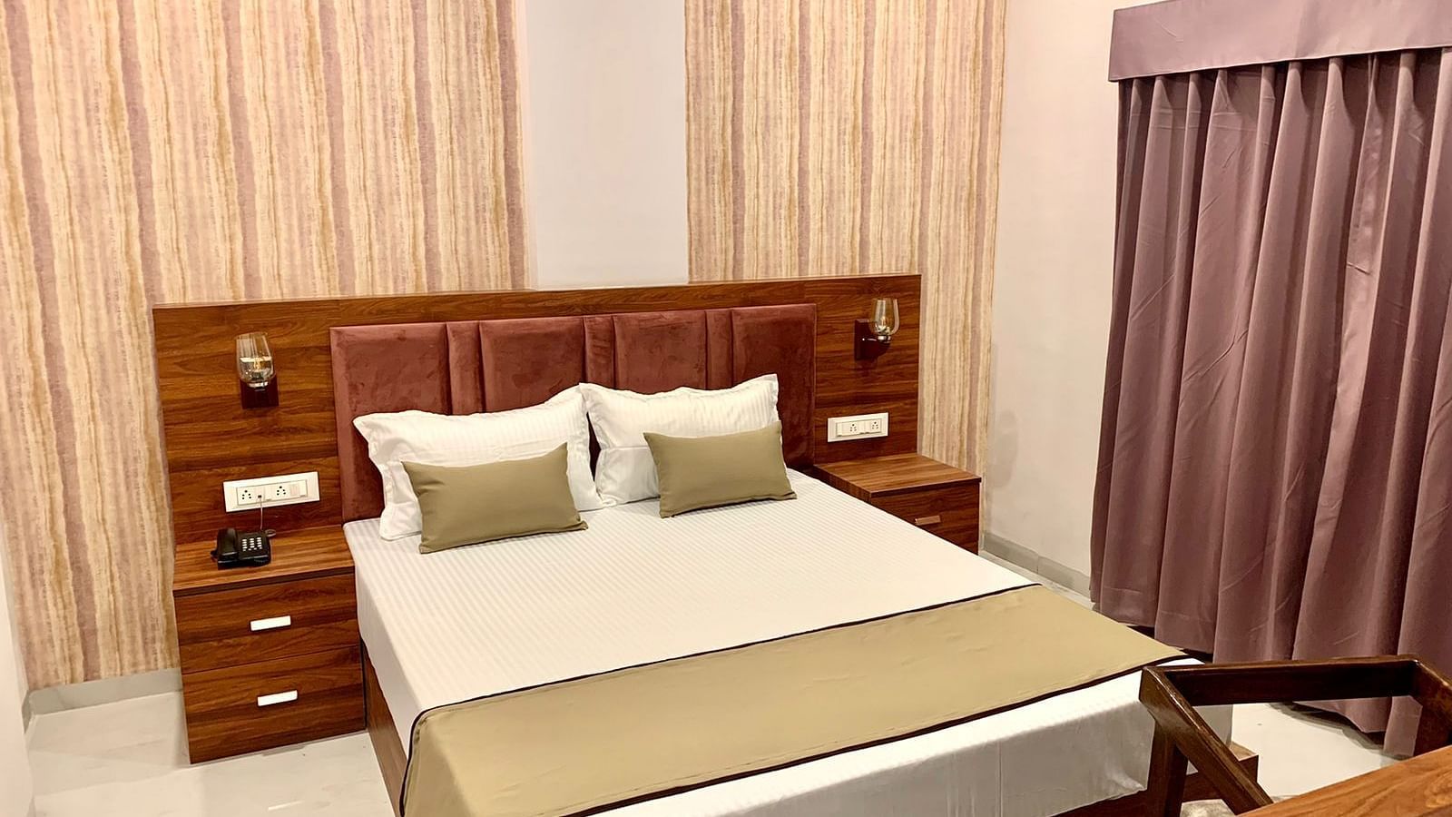 A front view of a bed with bedding and wooden headboard in a bedroom | Mumbai House Hotels