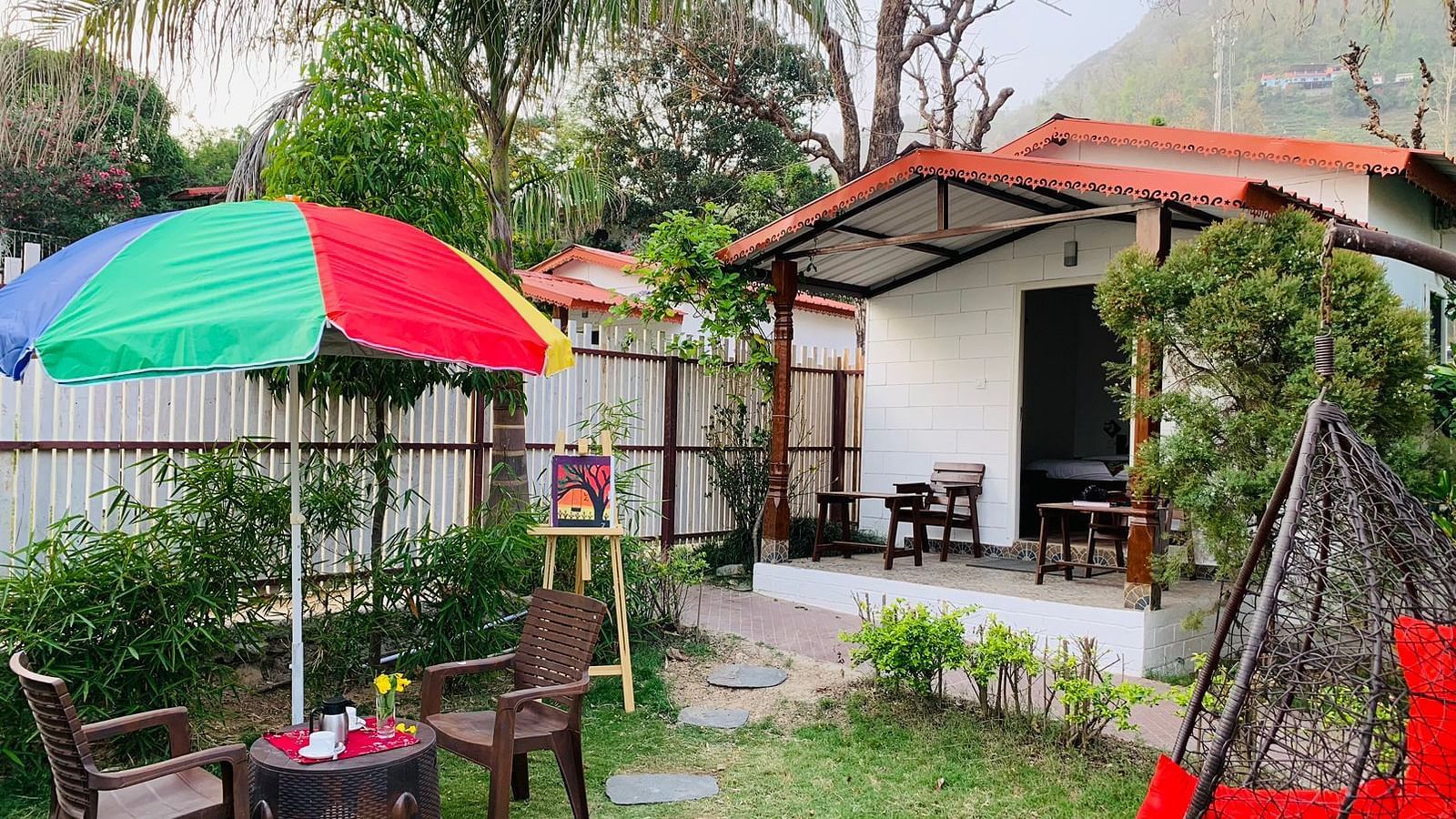 a garden behind one of the rooms with seats under a canopy in the garden - Neer Ganga Resorts