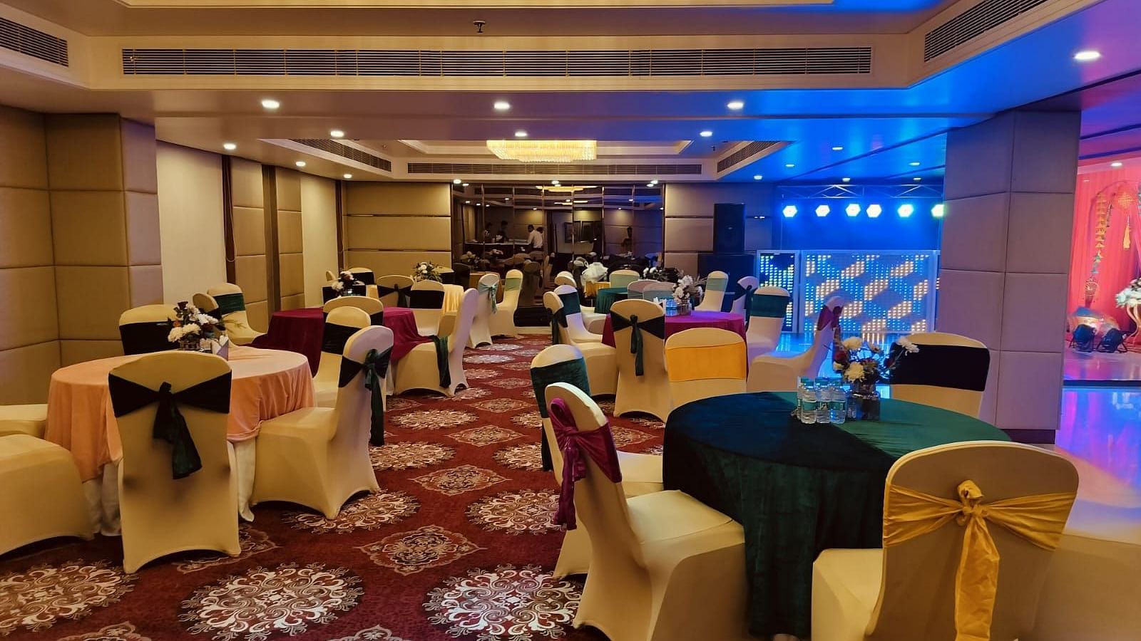 A beautiful banquet hall with carpet flooring and blue halogen lights lit up in the corner - Ramada by Wyndham, Ghaziabad, Vasundhara
