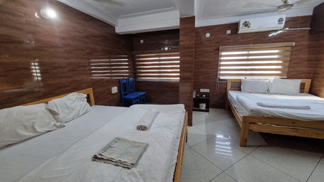 Comfortable family room with multiple beds and wooden wall panels at Dream Vision Guest House, Diu.
