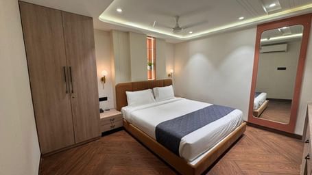 Comfortable bedroom at Hotel Mumbai House, Vijay Nagar, Indore, with soft lighting, spacious wardrobe, and refined interiors for a restful experience.