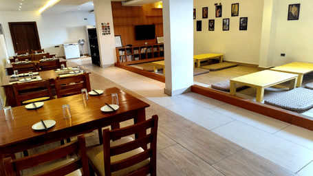Full view of the Ajito restaurant featuring two types of seating arrangements in a brightly-lit dining area at Full view of the Ajito restaurant featuring several dining tables arranged against the wall at one side at Ilara Hotels & Spa, Tada.