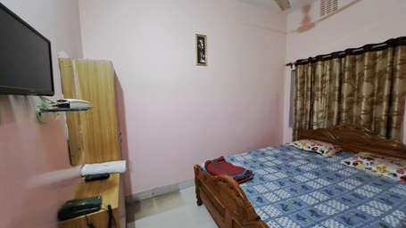 A Standard bedroom at Khairi Resorts displays a double bed, a wooden wardrobe, a TV, and patterned curtains.