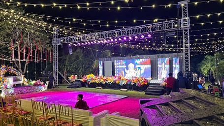 an outdoor event space with two stages, a well-lit decoration, and chairs arranged in a row with a complete audio visual system at Lords Hrim Akshara Resort, the best hotel in Basar, Telangana