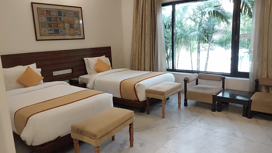 A twin-bedded room with large windows overlooking the greenery at A S Hotels, Khajuraho.