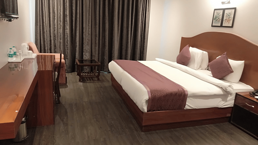 A bedroom with a double bed, desk, and television at A S Hotels, Khajuraho.