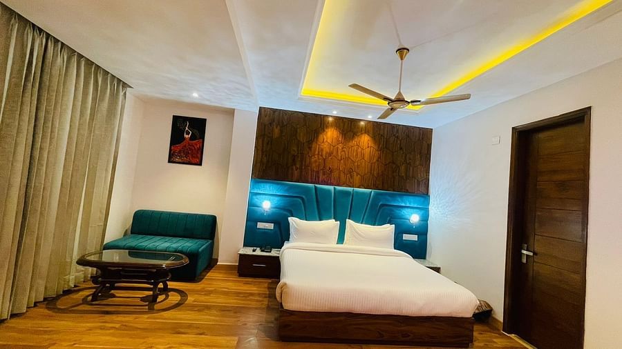 A large bed placed next to a sofa in Luxury Room With Balcony at DLS Ark Holiday Inn, Banikhet.