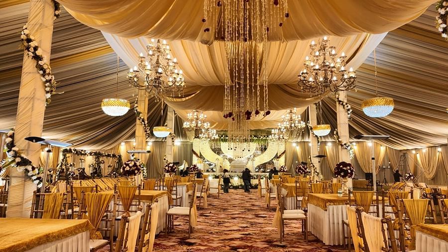 A beautifully decorated wedding hall with chandeliers, draped fabric, and tables set for guests.