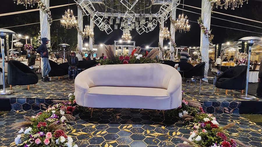 A wedding stage with a white sofa, floral arrangements, and chandeliers.
