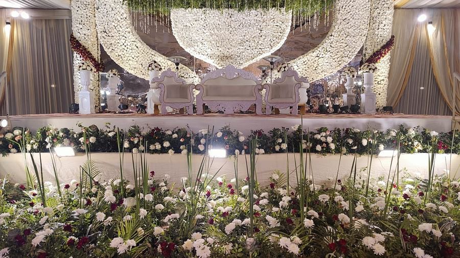 A lavishly decorated wedding stage with a large, ornate backdrop, a chandelier, and floral arrangements.