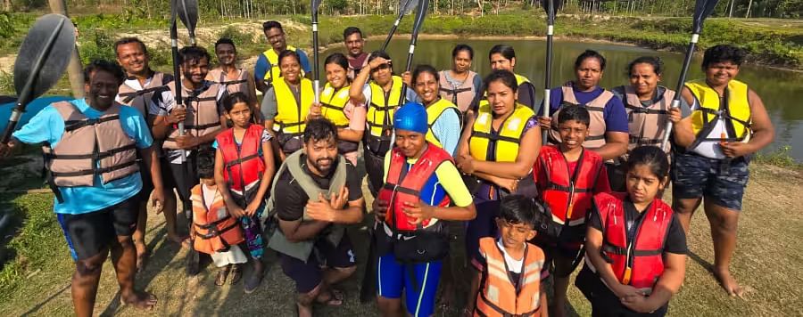 Large group in life jackets posing with paddles by a river, ready for a kayaking adventure - Evergreen County