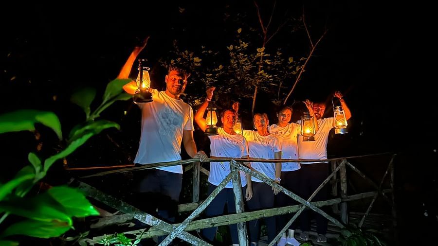 A group standing on a bridge at night, each holding a lantern, creating a warm, inviting atmosphere - Evergreen County