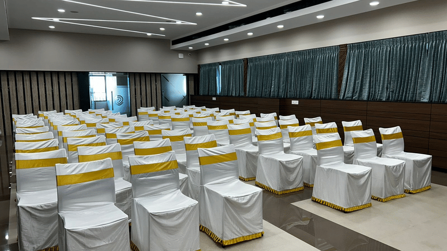Rows of white-covered chairs arranged in theatre style layout inside Gangai Hall at Hotel Grand Sabarees Madurai.